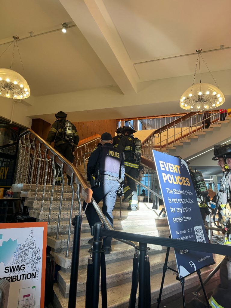 Firefighters and police heading upstairs past an event policies sign