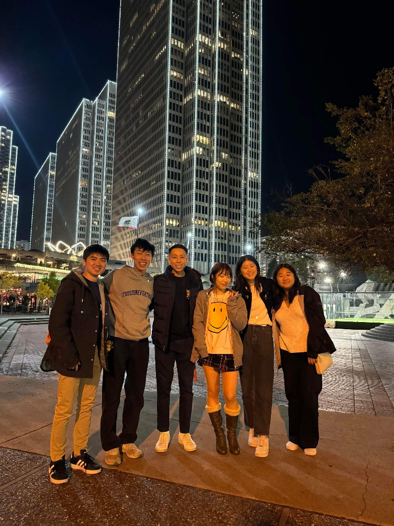 The team posing at night in front of city skyscrapers