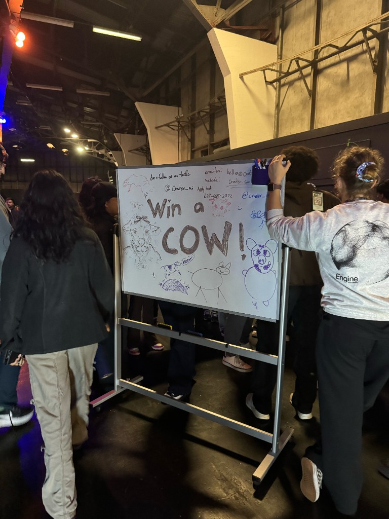 A whiteboard sign reading 'Win a Cow!' covered in doodles