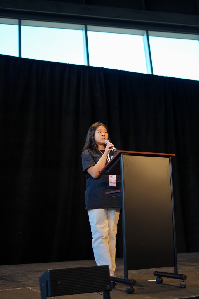 Flora speaking into a microphone at the podium during Cal Hacks 11.0